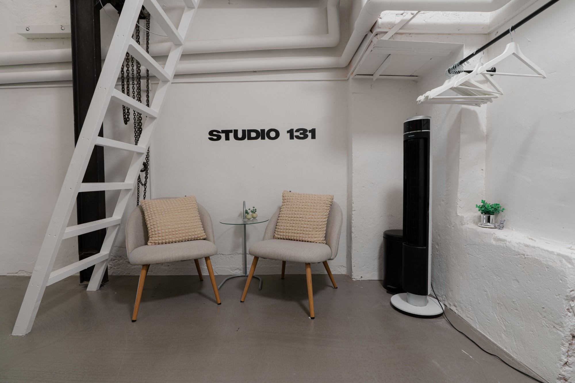 Studio 131 – fåtöljer och klädräcke vid väggskylten