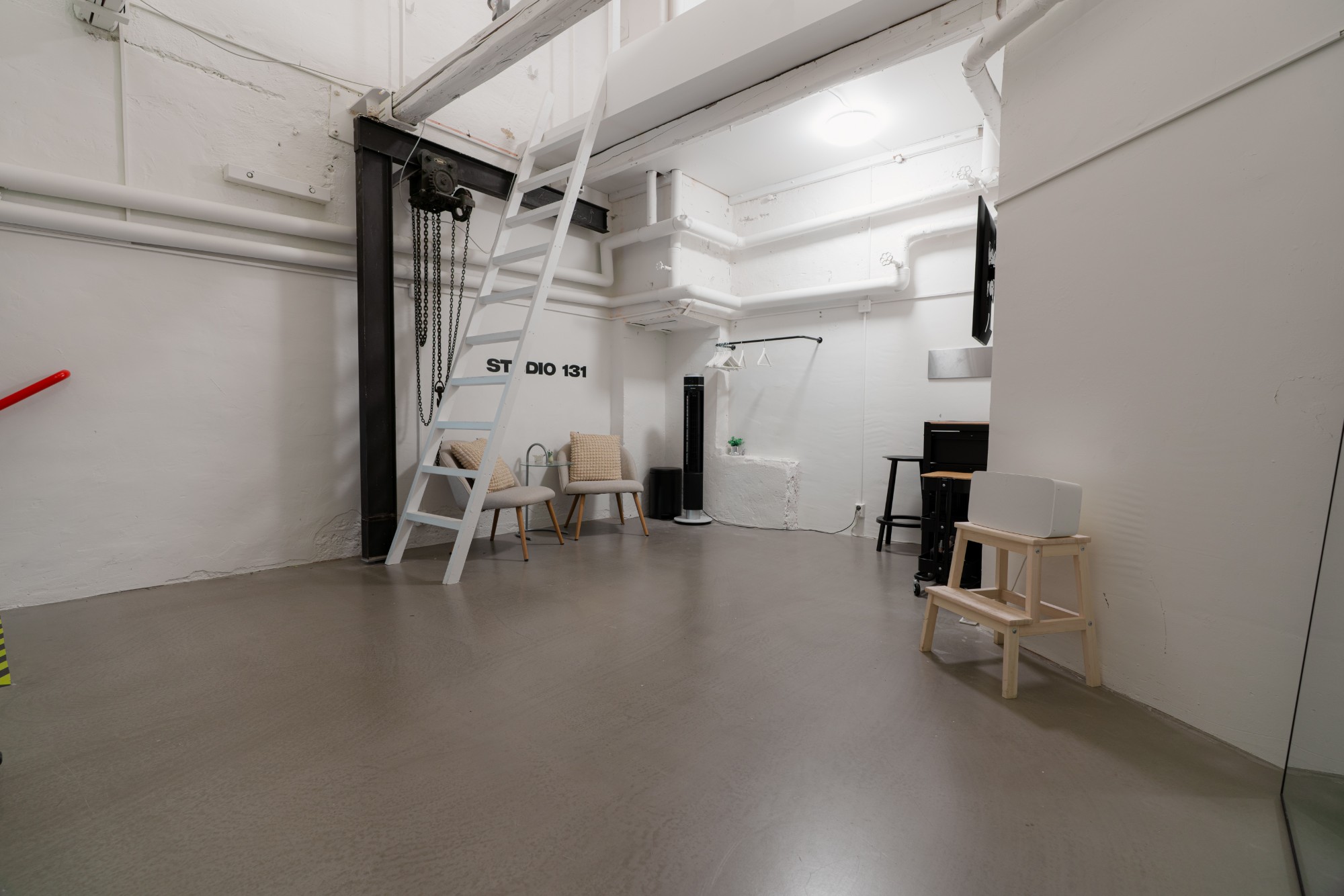 Studio 131 – hela studiolokalen med lofttrappa, betonggolv och sittgrupp